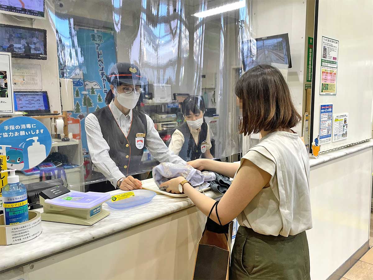 駅員に古着を渡す