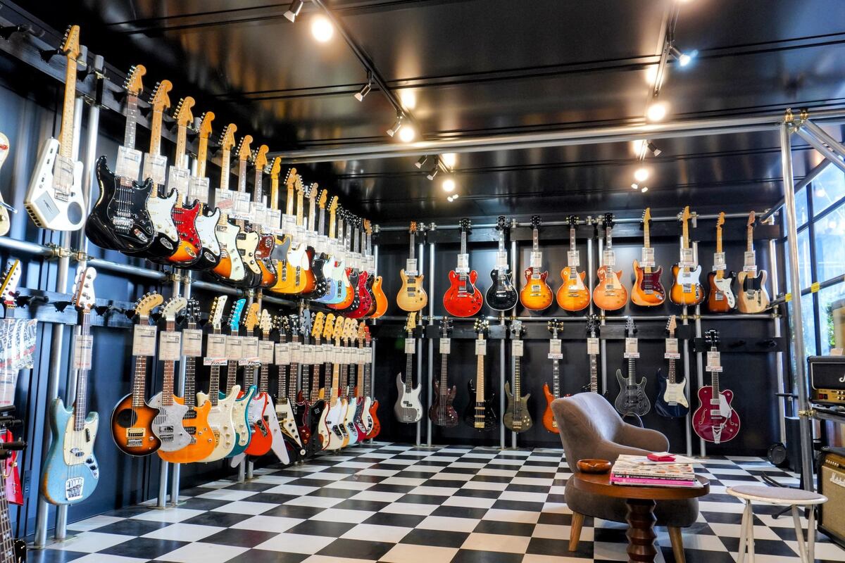 黒基調の店内にギターが並ぶ。ソファーに座って試奏も可能